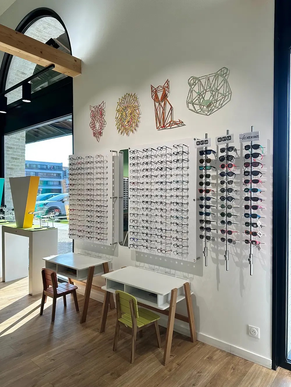 Le coin enfants : présentoirs de montures optiques et solaires, décorations animales en bois
